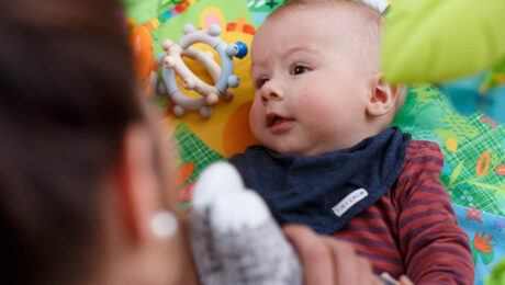 Baby spielt mit Mutter am Boden