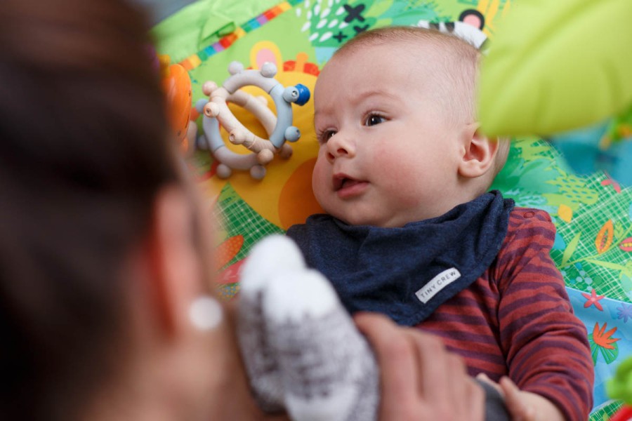 Baby spielt mit Mutter am Boden