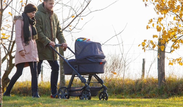 Eltern gehen mit Kinderwagen spazieren