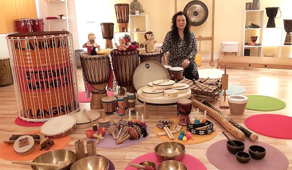 Frau sitz in Ihrem Studio vor vielen Musikinstrumenten