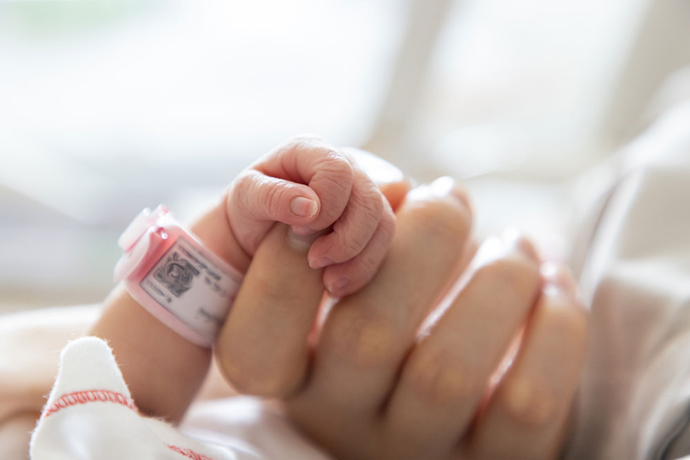 Mutter hält Babys Händchen nach der Geburt