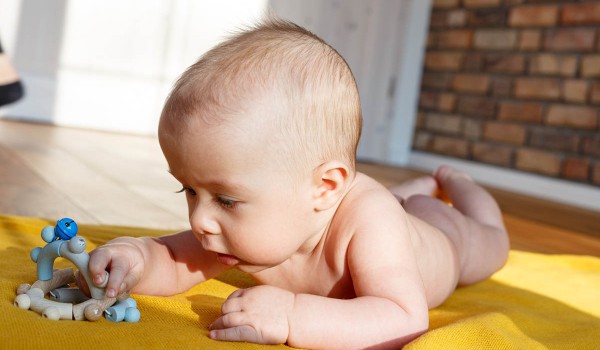 Baby liegt bäuchlings auf einer Decke und hebt das Köpfchen