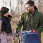 Paar spaziert mit Kinderwagen im Park.