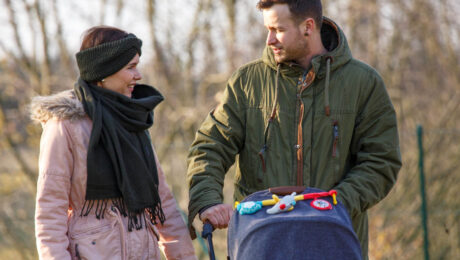 Paar spaziert mit Kinderwagen im Park.