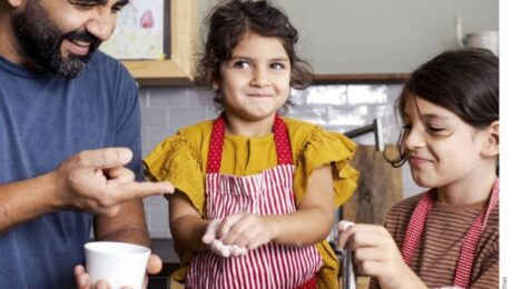 Vater und zwei Töchter backen gemeinsam in der Familienküche.